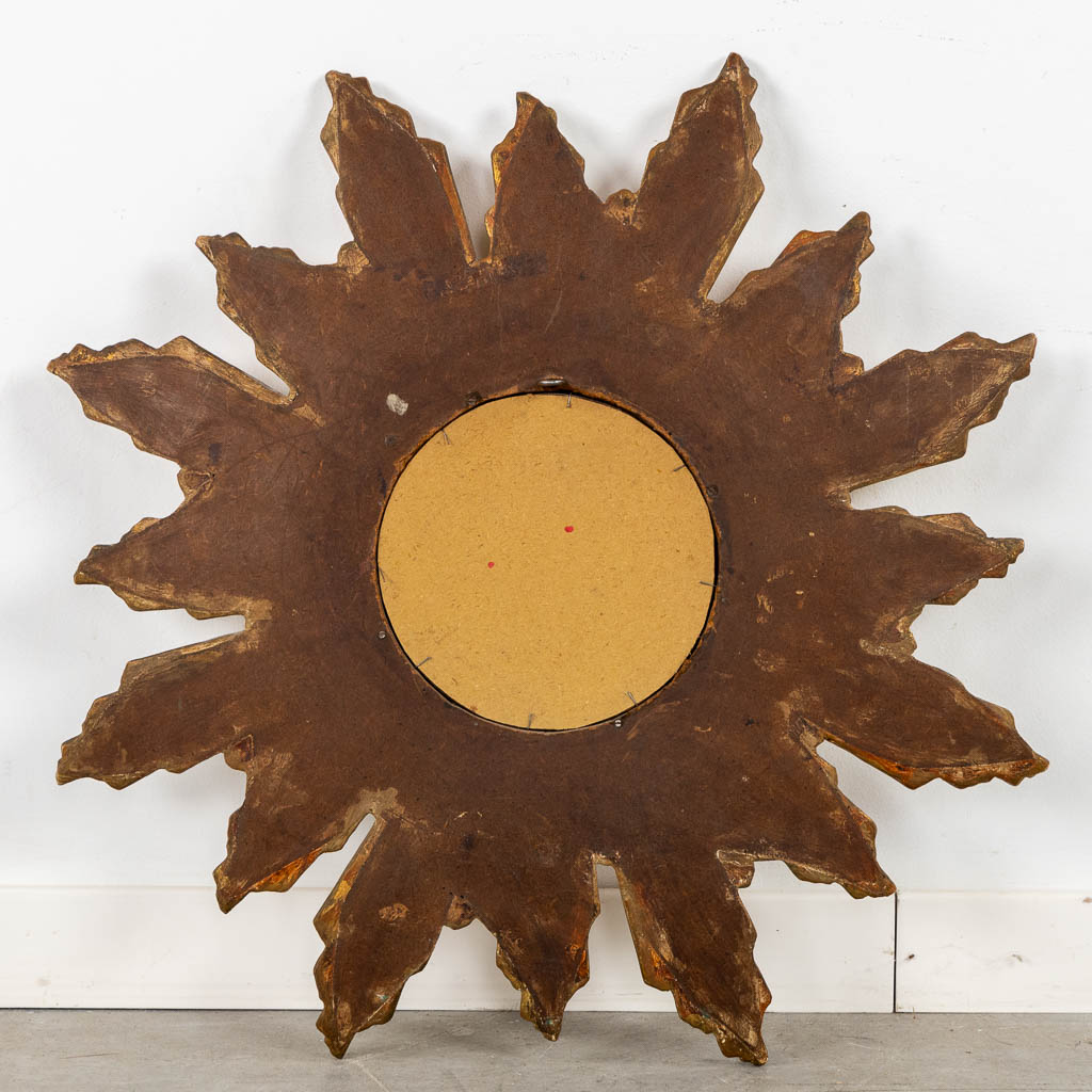 A wood-sculptured sunburst mirror with bent rays, convex glass.