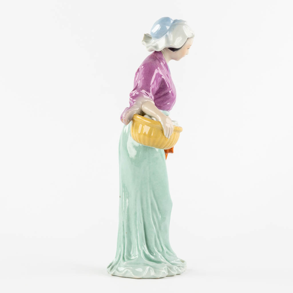 Een Chinees porseleinen figuur van een dame met mand. (L:11 x W:18 x H:32,5 cm)