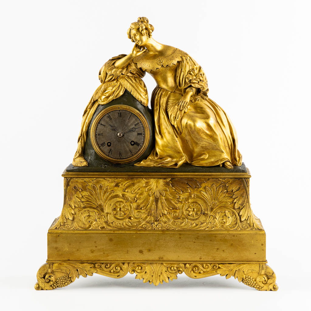 A mantle clock with a resting lady, gilt bronze. France, 19th C. (L:13 x W:38 x H:43 cm)