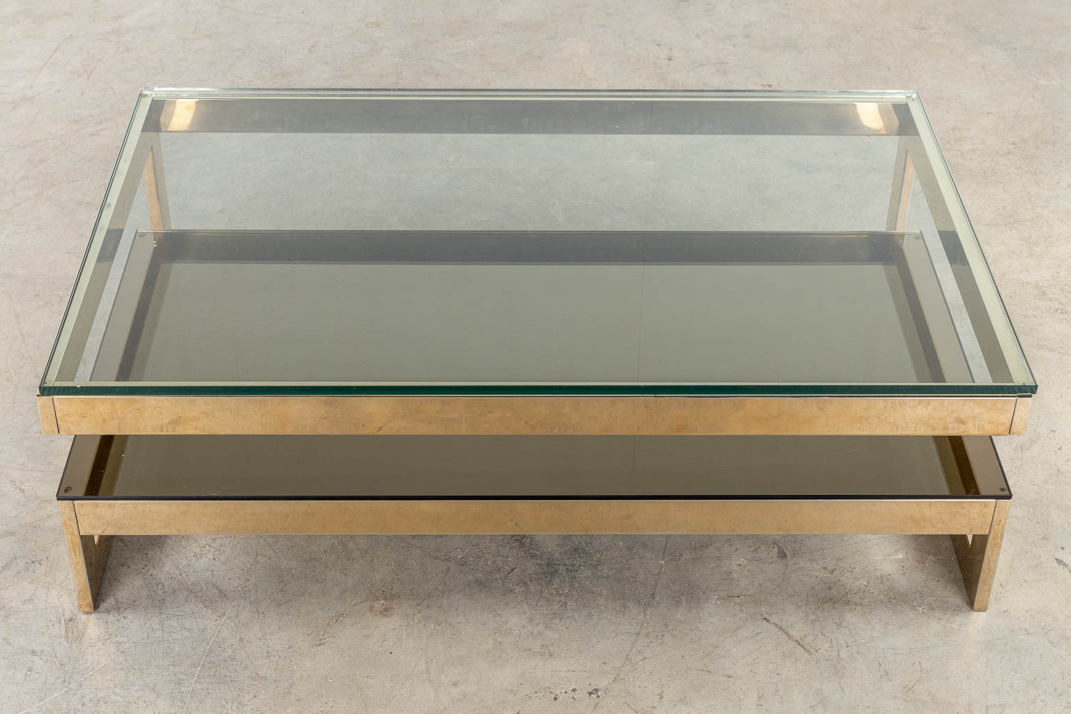 Belgo Chrome, een G-shape salontafel. Verguld metaal en glas. (L:120 x W:75 x H:38 cm)