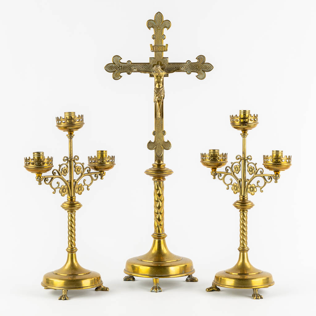 An altar crucifix with two matching candelabra, brass in a Gothic Revival style. (W:23 x H:58 cm)