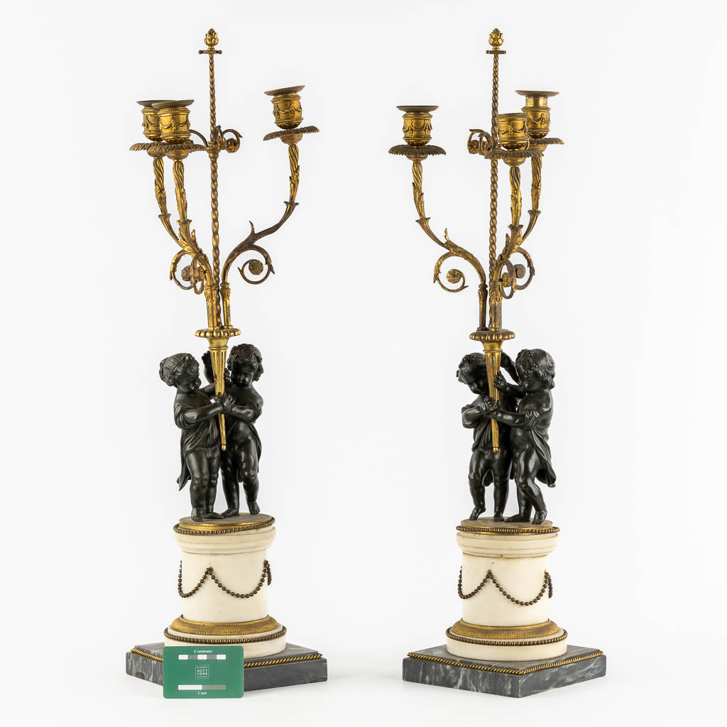 A pair of Marble, gilt and patinated bronze candelabra with putti, Louis XVI style, 19th C. (L:16,5 x W:16,5 x H:71,5 cm)