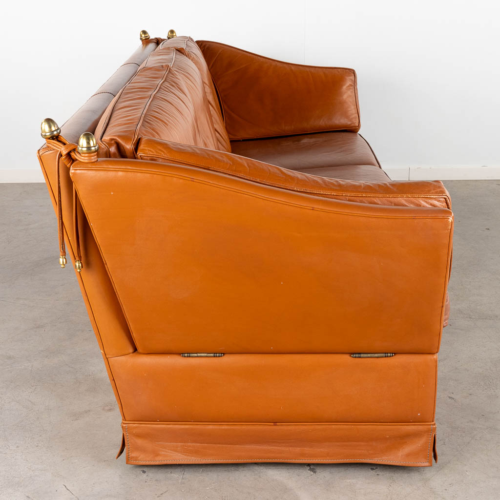 Een leder drie-persoon zetel in de stijl van Maison Jansen. (D:93 x W:240 x H:88 cm)