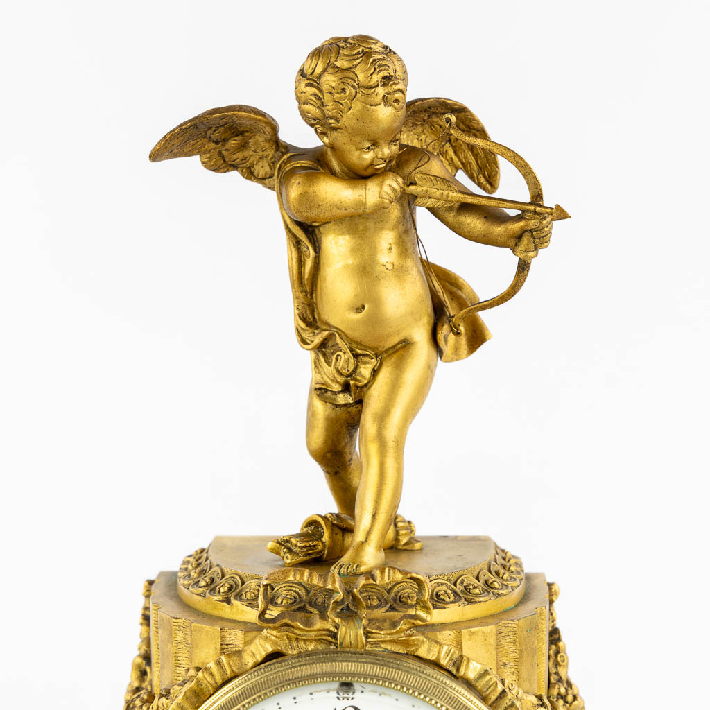 A three-piece mantle garniture clock, Cupid. Gilt bronze and Carrara marble. (L:13 x W:17 x H:37 cm)