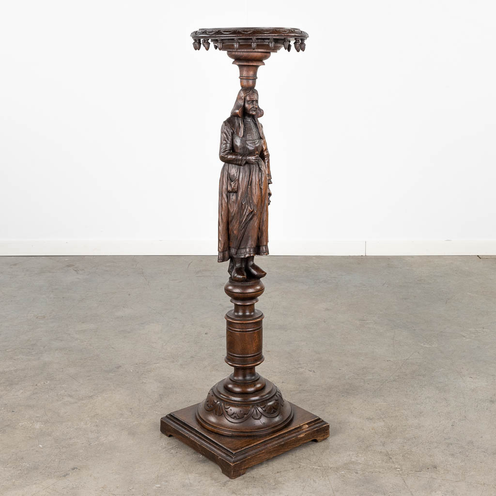 A pedestal with a wood sculptured figurine in Breton style. Circa 1900. (L: 31,5 x W: 31,5 x H: 107 cm)