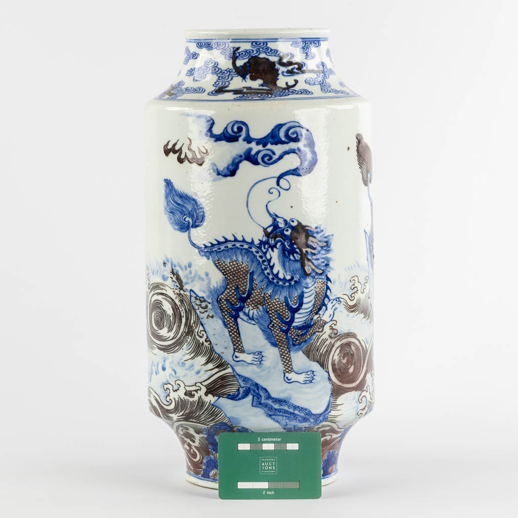 A Chinese Rouleau vase with a blue, black and white Foo Dog. Kangxi mark, 19th C. (H:39 x D:29 cm)