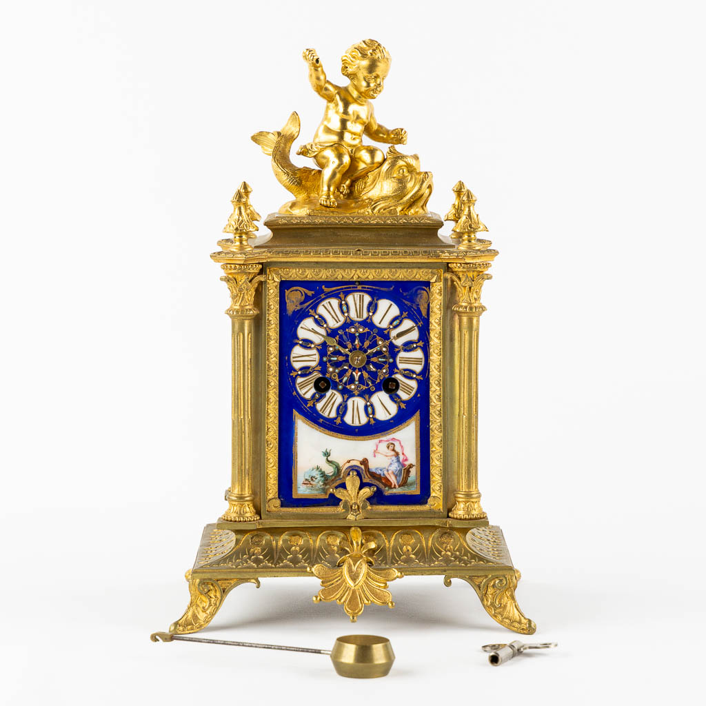 A mantle clock, gilt bronze mounted with porcelain. 19th C.