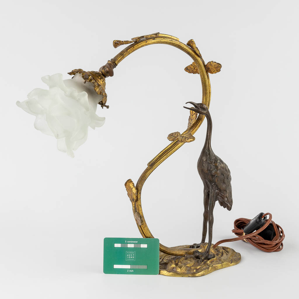 A table lamp with a large bird, probably a Heron. Patinated and gilt bronze, circa 1900. (W:33 x H:37 cm)