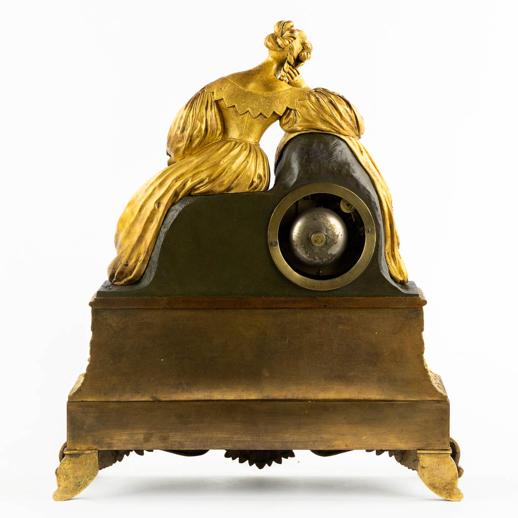 A mantle clock with a resting lady, gilt bronze. France, 19th C. (L:13 x W:38 x H:43 cm)