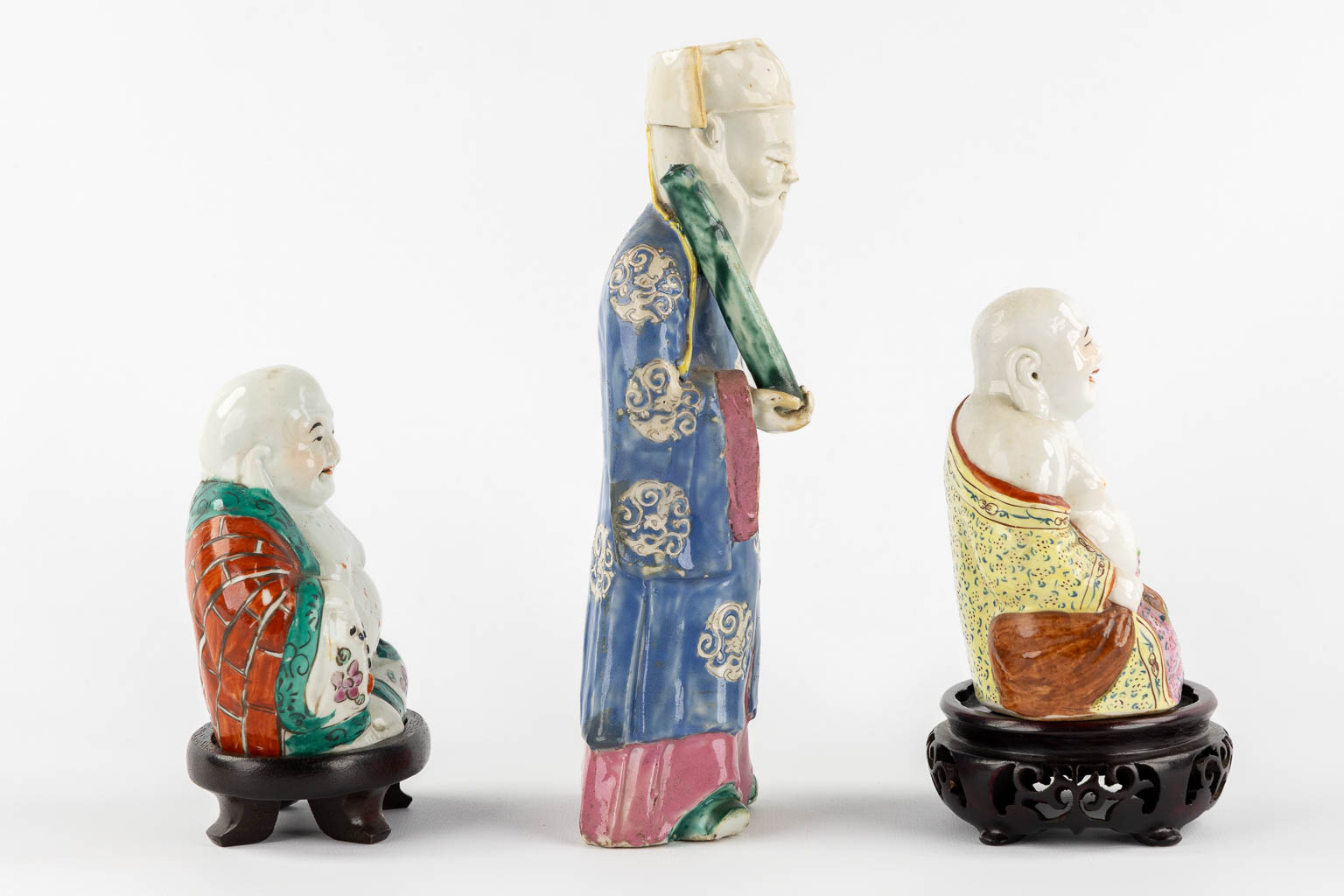 Drie polychroom porseleinen figuren van Boeddha en Lao Tse. (L:7 x W:10 x H:24 cm)