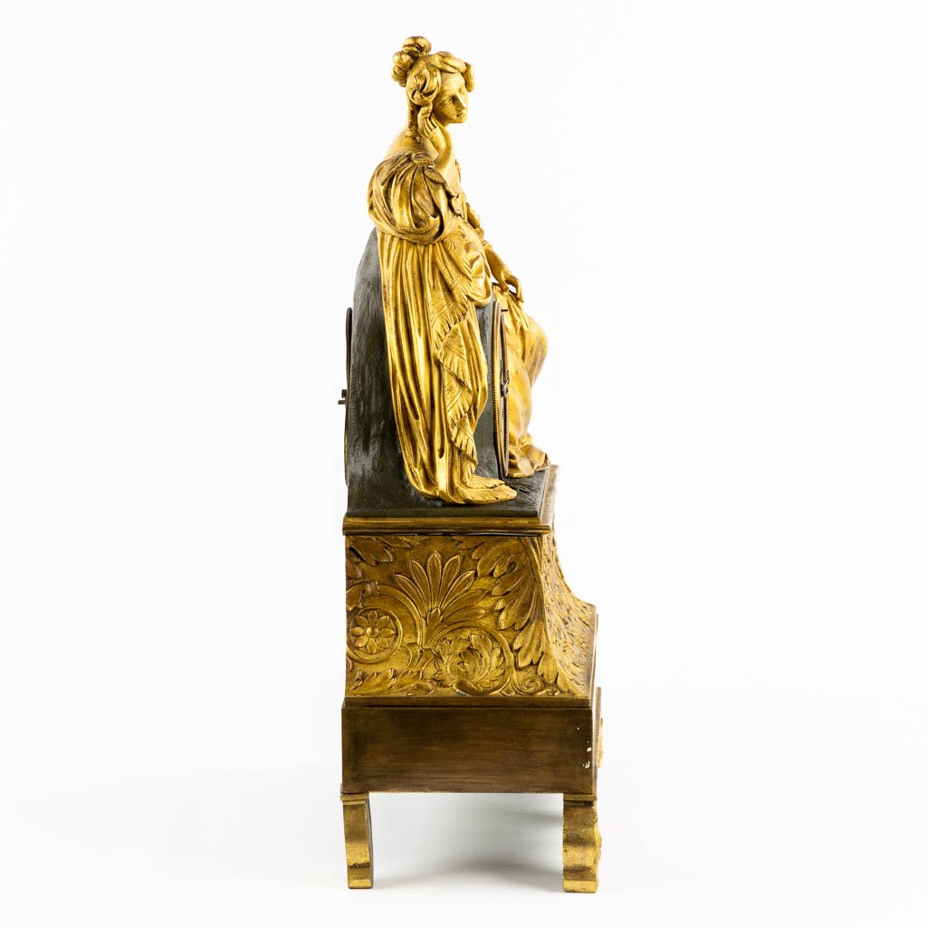 A mantle clock with a resting lady, gilt bronze. France, 19th C. (L:13 x W:38 x H:43 cm)