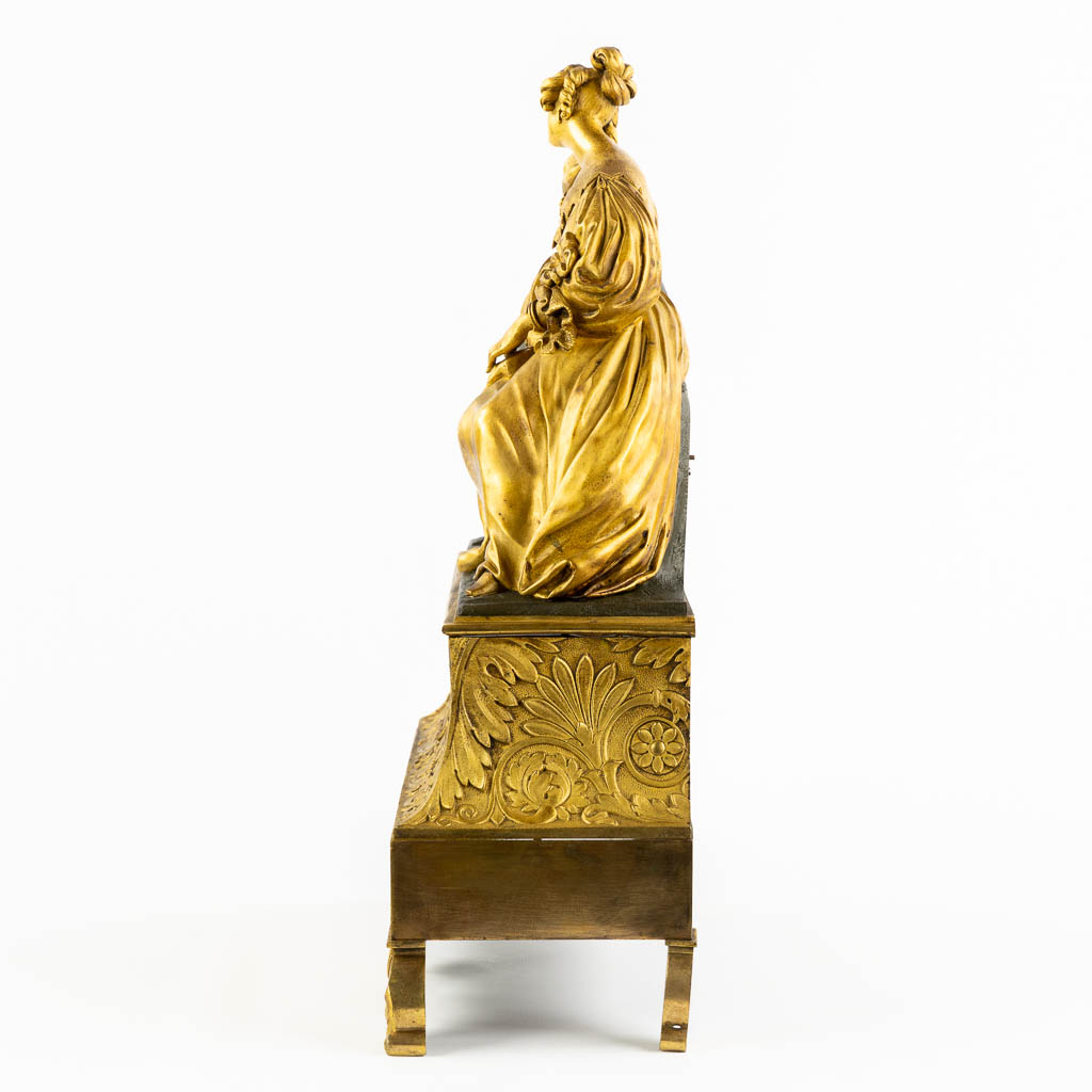 A mantle clock with a resting lady, gilt bronze. France, 19th C. (L:13 x W:38 x H:43 cm)