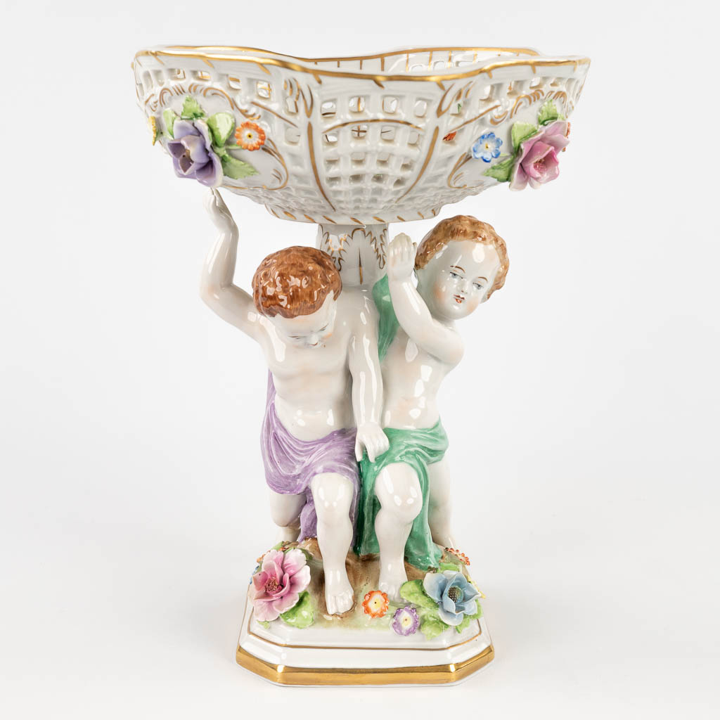 Plaue Schierholz 1817, a porcelain tazza decorated with boys holding up a basket. 20th C. (L:19 x W:19,5 x H:27 cm)