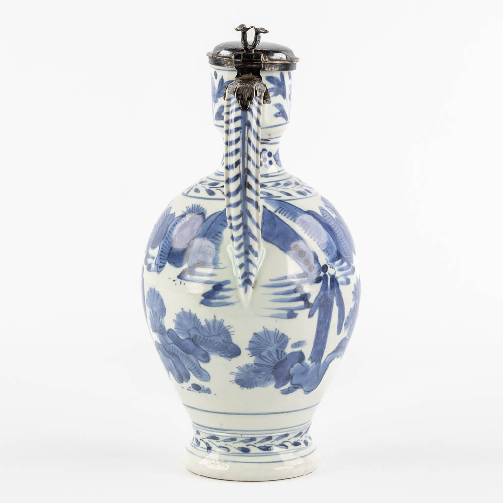 A Chinese pitcher, blue-white mounted with silver, Netherlands, 17th C. (L:12 x W:13 x H:25 cm)