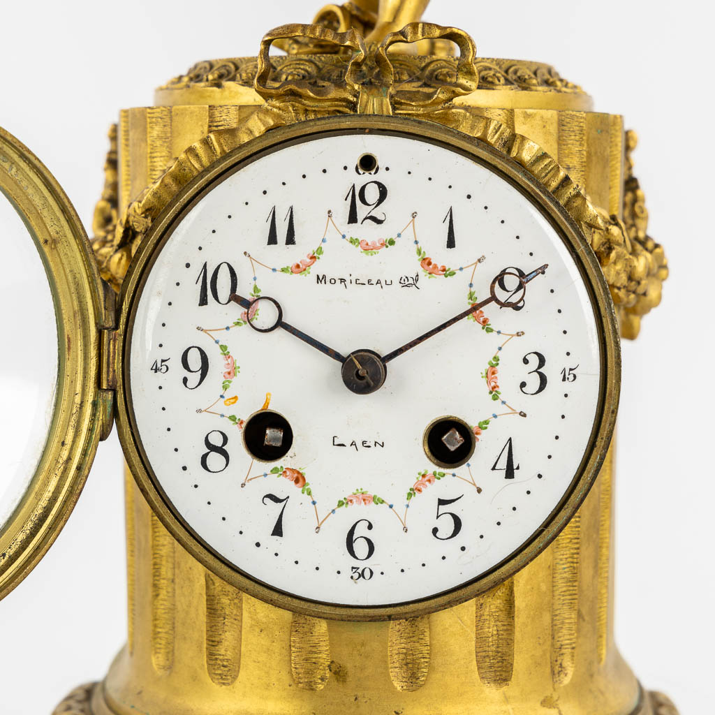 A three-piece mantle garniture clock, Cupid. Gilt bronze and Carrara marble. (L:13 x W:17 x H:37 cm)