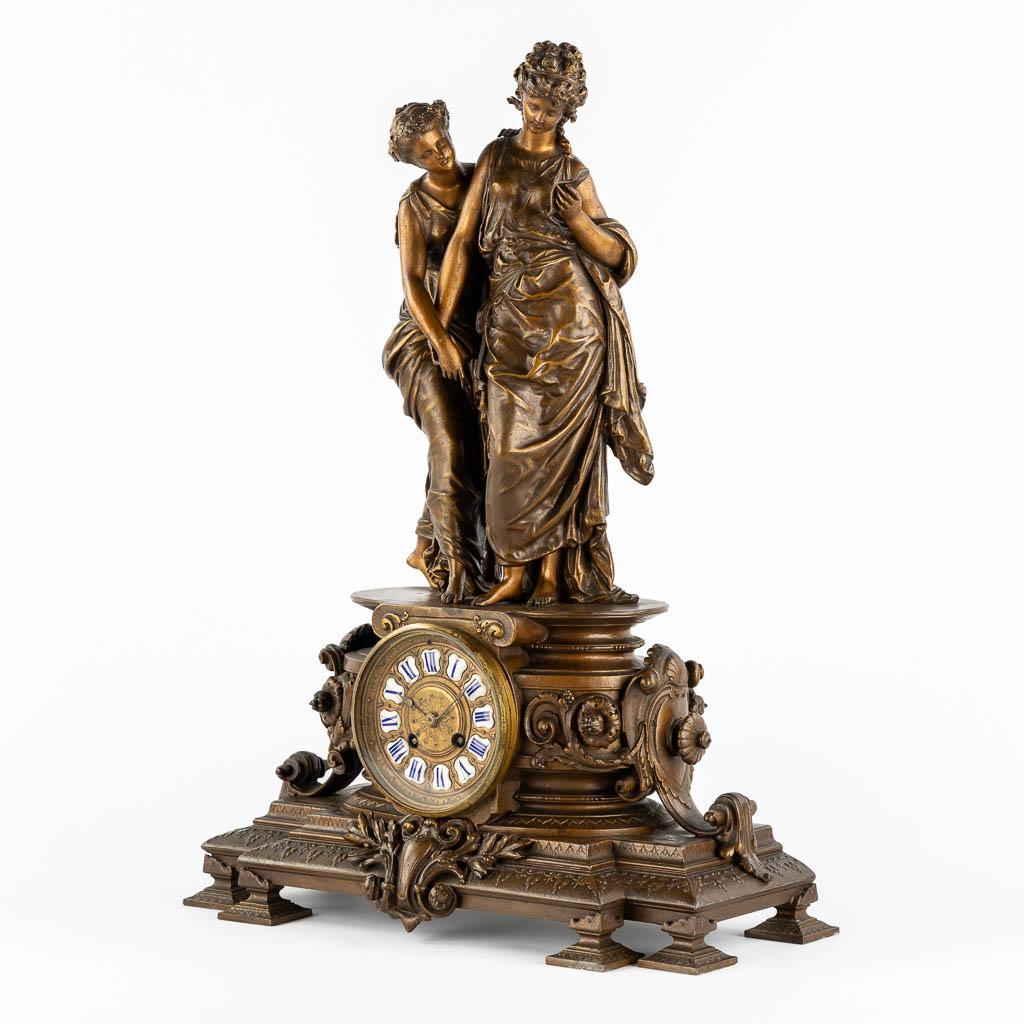 A large mantle clock with two ladies, patinated spelter. Circa 1900. (L:18 x W:42 x H:58 cm)