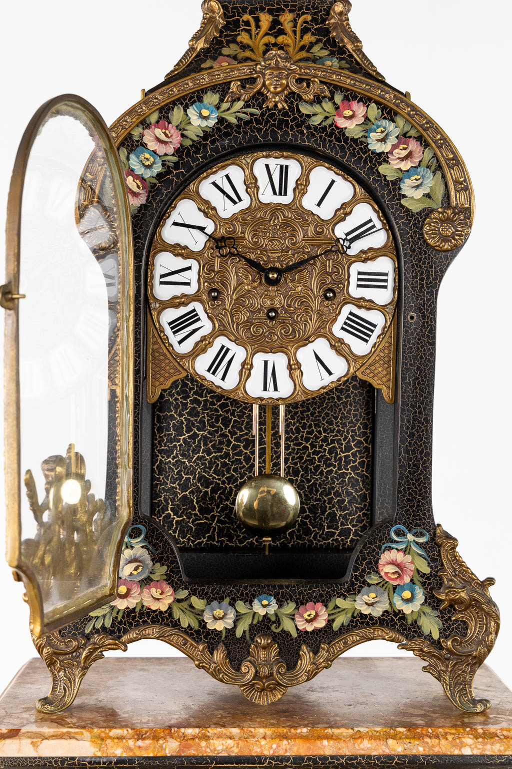 A cartel clock on a base, floral decor and mounted with putti. 20th C. (L:25 x W:44 x H:193 cm)