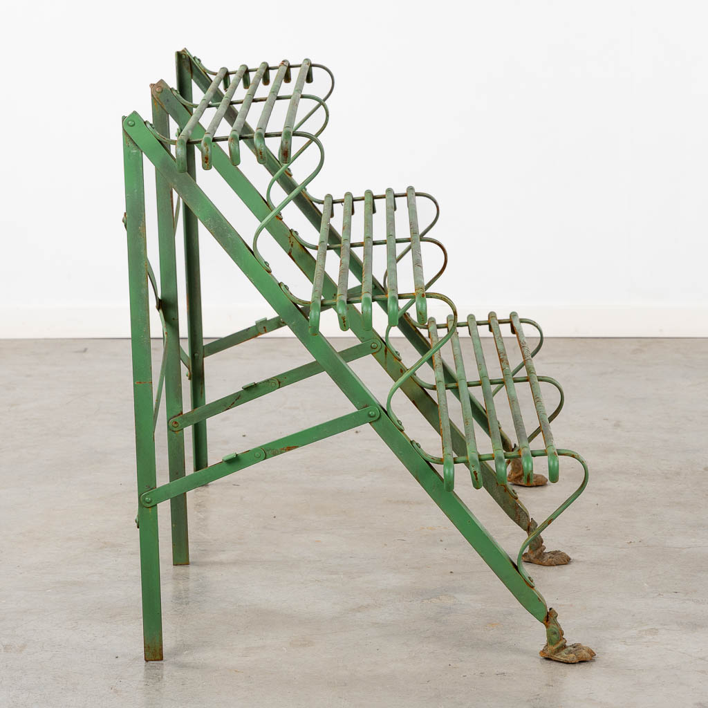 A green-patinated metal garden rack standing on claw feet. (L:60 x W:124 x H:75 cm)