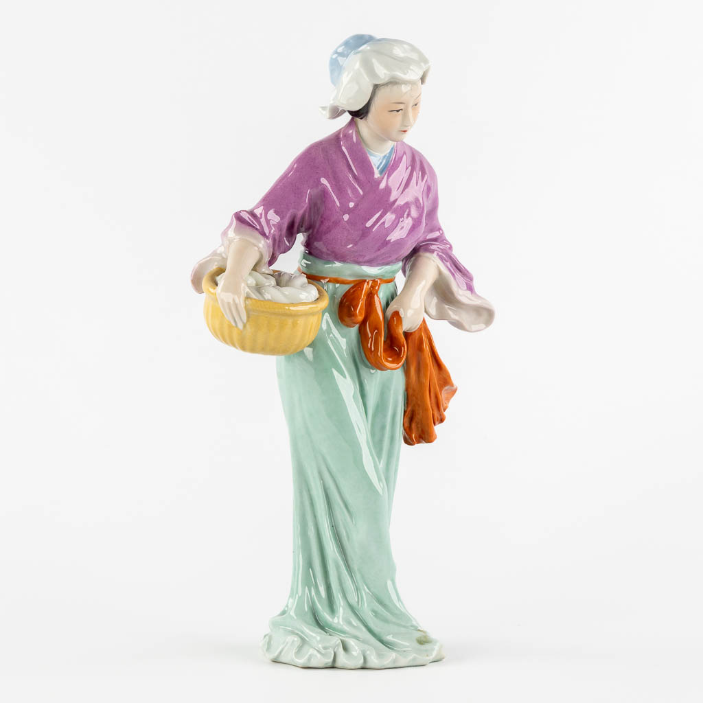 Een Chinees porseleinen figuur van een dame met mand. (L:11 x W:18 x H:32,5 cm)