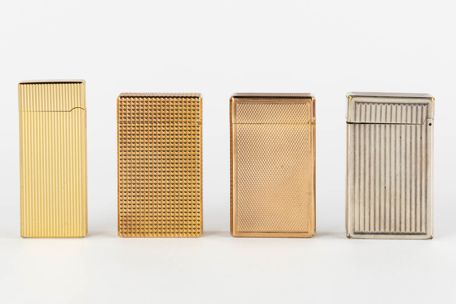 ST. Dupont, Three gold and silver plated lighters, added a Givency lighter. (L:1 x W:3,5 x H:6 cm)