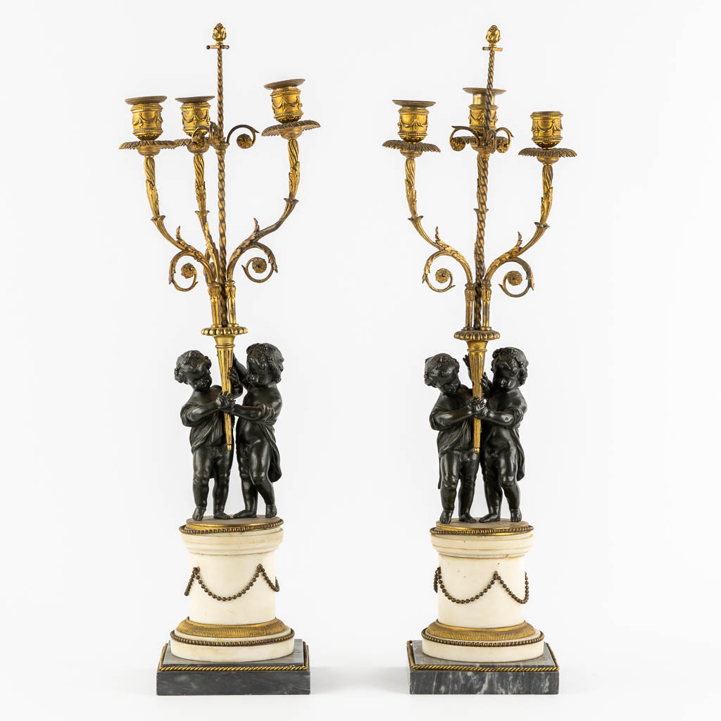 A pair of Marble, gilt and patinated bronze candelabra with putti, Louis XVI style, 19th C. (L:16,5 x W:16,5 x H:71,5 cm)