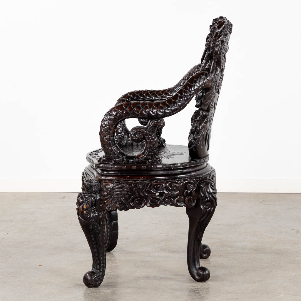 A Chinese sculptured hardwood armchair with a dragon decor. 