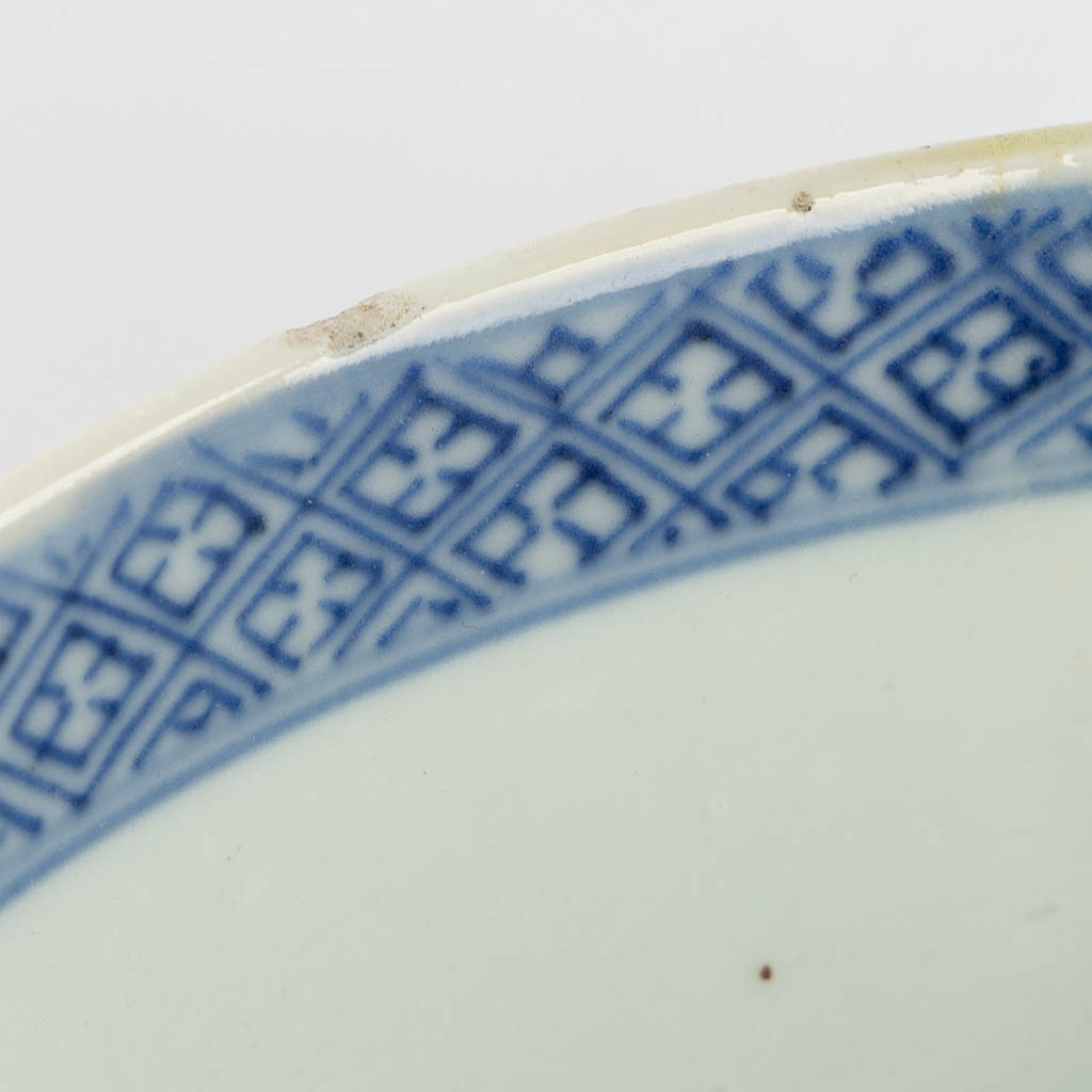 A pair of Chinese bowls, blue-white with a floral and pomegranate decor. 19th C. (H:8,5 x D:18 cm)